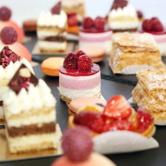A variety of mini sized cakes on the table.